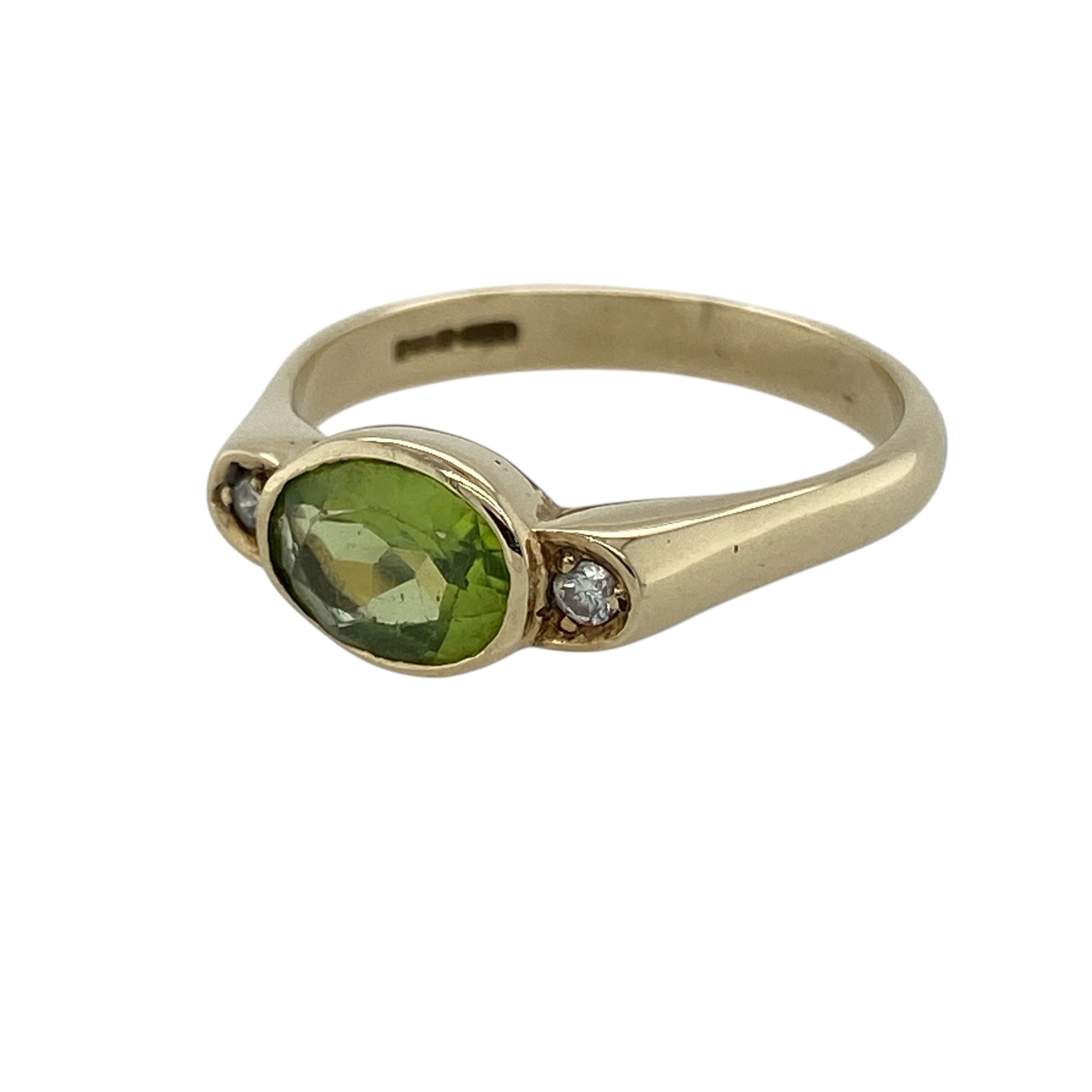Add fresh colour and timeless elegance to your jewellery collection with this pre-owned 9ct yellow gold diamond and peridot ring, featuring a vibrant oval gemstone with delicate diamond accents—perfect for special occasions, gifting, or sophisticated everyday wear.

Design: The ring showcases a striking oval-cut peridot stone measuring approximately 8mm by 6mm, complemented by a sparkling diamond on either side to create a balanced and elegant gemstone design.