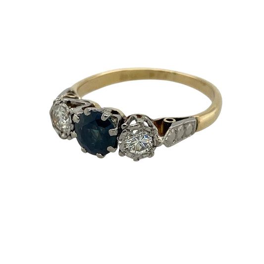 Add timeless elegance and luxurious sparkle to your jewellery collection with this pre-owned 18ct yellow gold illusion set diamond and sapphire trilogy ring, featuring a classic three-stone design with rich colour and refined brilliance—perfect for special occasions, anniversaries, or sophisticated everyday wear.

Design: The ring showcases a vibrant round sapphire centre stone measuring approximately 5.5mm in diameter, flanked by illusion set diamonds on either side.
