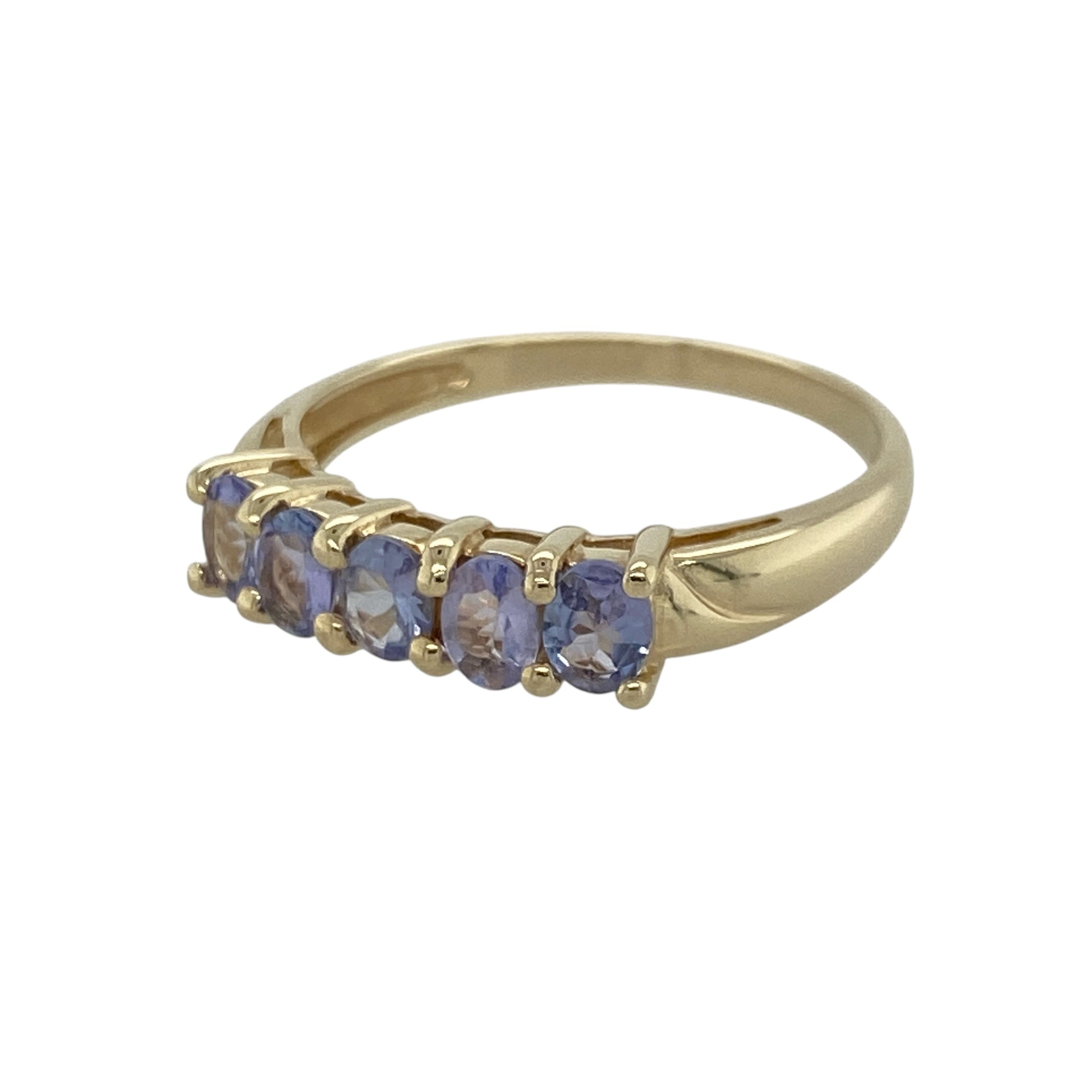 Add elegant colour and timeless sparkle to your jewellery collection with this pre-owned 9ct yellow gold tanzanite coloured stone set band ring, featuring a classic multi-stone design with sophisticated everyday appeal—perfect for stacking, gifting, or special occasion wear.

Design: The ring features a row of oval tanzanite coloured stones, each measuring approximately 4mm by 3mm, creating a refined and eye-catching band design with rich violet-blue tones.