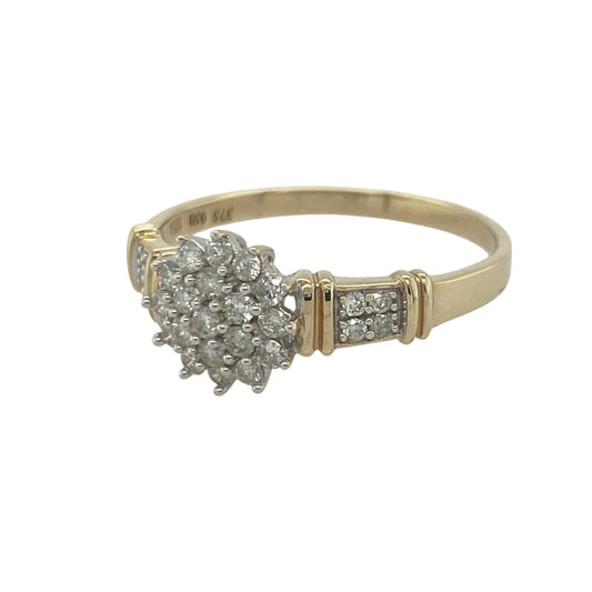 Add exceptional sparkle and timeless elegance to your jewellery collection with this pre-owned 9ct yellow gold diamond cluster ring, featuring diamond-set shoulders and an impressive multi-stone design—perfect for special occasions, gifting, or luxurious everyday wear.

Design: The ring showcases a dazzling diamond cluster centre measuring approximately 9mm high at the front, complemented by sparkling diamond-set shoulders that enhance the overall brilliance of the piece.