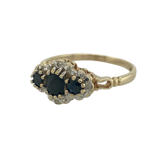 Add timeless elegance and rich colour to your jewellery collection with this pre-owned 9ct yellow gold diamond and sapphire trilogy cluster ring, featuring a classic three-stone design enhanced with sparkling diamond halos—perfect for special occasions, gifting, or sophisticated everyday wear.

Design: The ring showcases three beautiful sapphires arranged in a trilogy setting, with a central sapphire measuring approximately 4mm in diameter and two side sapphires measuring approximately 3mm in diameter each.