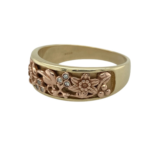 Add a touch of Welsh heritage and symbolic elegance to your jewellery collection with this pre-owned 9ct yellow and rose gold diamond Clogau flower band ring, featuring a beautifully detailed design inspired by nature and tradition—perfect for gifting, special occasions, or meaningful everyday wear.

Design: The ring features an intricate floral band design measuring approximately 7mm wide at the front, incorporating a daffodil, Tudor rose, and the iconic Tree of Life motif.