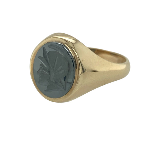 Add a touch of classical style and bold character to your jewellery collection with this pre-owned 9ct yellow gold hematite Centurion signet ring, featuring a distinctive design with timeless appeal—perfect for collectors, gifting, or everyday statement wear.

Design: The ring showcases a striking oval hematite stone measuring approximately 12mm by 10mm, beautifully carved with a traditional Centurion profile.