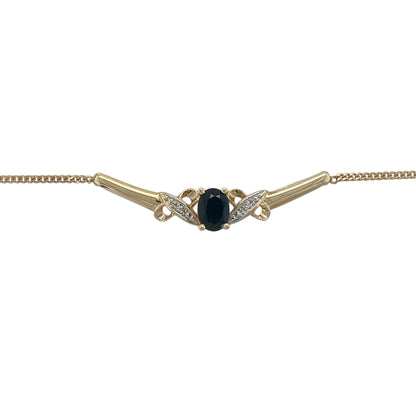 Add timeless elegance and vibrant colour to your jewellery collection with this pre-owned 9ct yellow gold diamond and sapphire necklace. Featuring a beautiful oval sapphire framed by sparkling diamonds on a graceful curved bar design, this sophisticated necklace is perfect for both everyday wear and special occasions.

Design: The necklace showcases an elegant curved bar centrepiece featuring an oval-cut sapphire measuring approximately 7mm by 5mm.