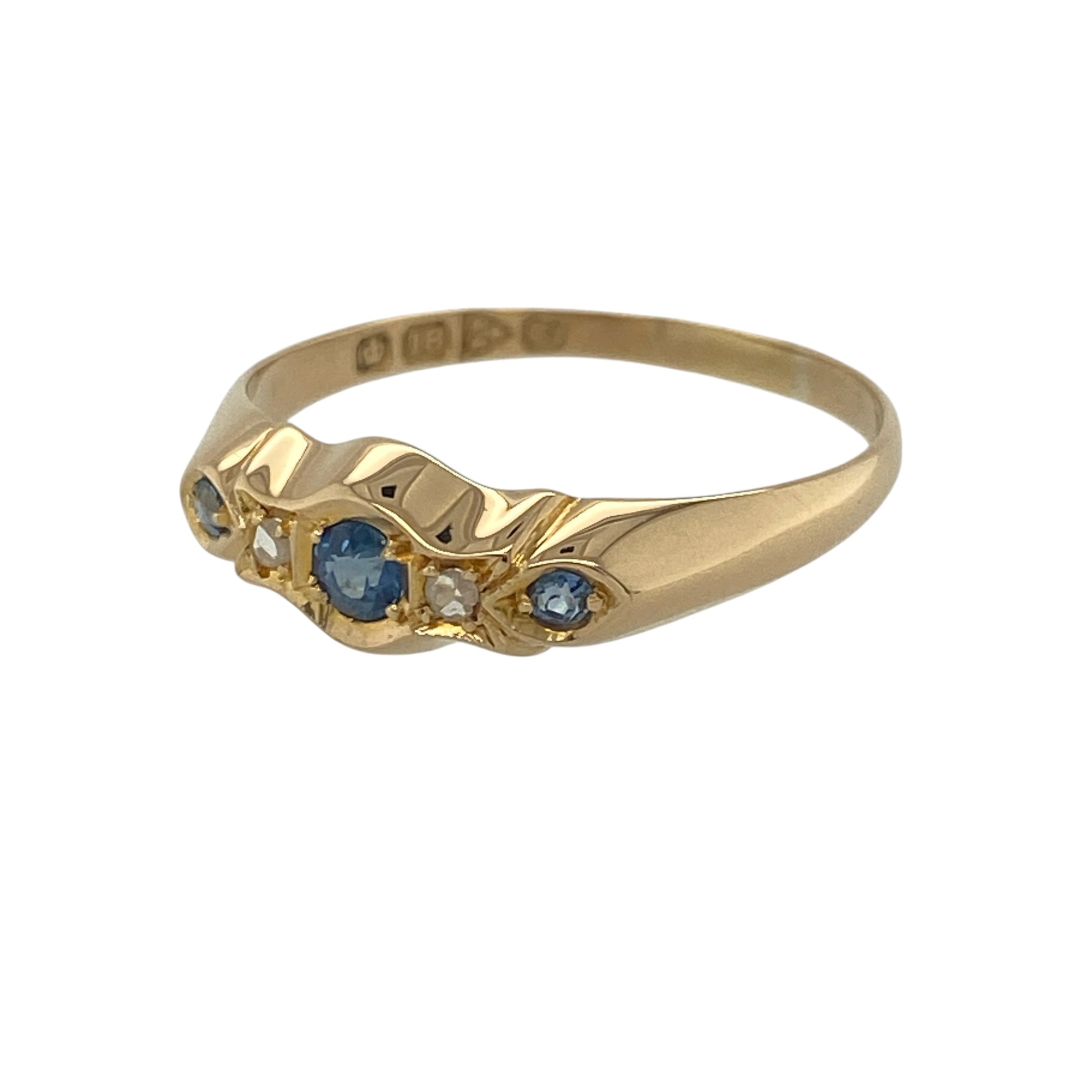 Add timeless elegance and rich colour to your jewellery collection with this pre-owned 18ct yellow gold diamond and sapphire band ring. Featuring a classic five-stone arrangement with vibrant sapphires and sparkling diamonds, this beautifully balanced design offers enduring sophistication and charm.

Design: The ring is centred by a round sapphire measuring approximately 3mm in diameter, creating a striking focal point.