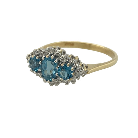 Add a touch of luxury and vibrant colour to your jewellery collection with this pre-owned 18ct yellow gold diamond and blue topaz trilogy cluster ring. Featuring three beautiful blue topaz gemstones accented with sparkling diamonds, this elegant ring offers a striking combination of brilliance and colour.

Design: The ring showcases a stunning trilogy arrangement with an oval-cut blue topaz centre stone measuring approximately 6mm by 4mm, flanked by two round blue topaz stones measuring approximately 4mm