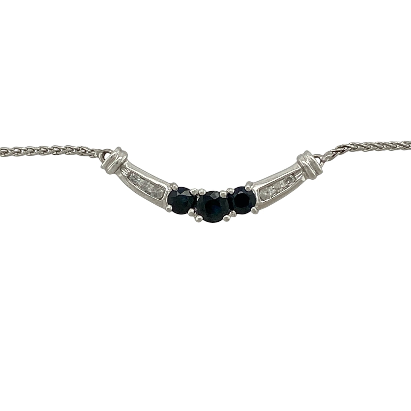 Add timeless elegance and vibrant colour to your jewellery collection with this pre-owned 10ct white gold diamond and sapphire curved bar necklace, featuring a graceful arrangement of sapphires and sparkling diamonds—perfect for everyday sophistication or special occasions.

Design: The necklace showcases an elegant curved bar design with a round sapphire measuring approximately 4mm in diameter at the centre, flanked by two round sapphires measuring approximately 3mm in diameter.