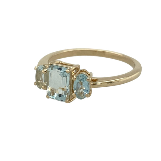 Add a splash of fresh colour to your jewellery collection with this pre-owned 9ct yellow gold aqua-coloured stone trilogy ring, featuring three beautifully matched stones in a timeless trilogy design—perfect for everyday elegance or special occasions.

Design: The ring showcases a striking rectangular-cut aqua-coloured centre stone measuring approximately 7mm by 5mm, flanked by two elegant oval-cut aqua-coloured side stones measuring approximately 5mm by 3mm each.