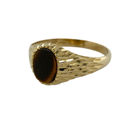 Add classic character to your jewellery collection with this pre-owned 9ct yellow gold tiger's eye signet ring, featuring a striking oval tiger's eye gemstone framed by an eye-catching diamond-cut textured surround.

Design: The ring showcases an elegant oval tiger's eye gemstone measuring approximately 8mm by 6mm, displaying the distinctive golden-brown chatoyancy for which tiger's eye is admired.