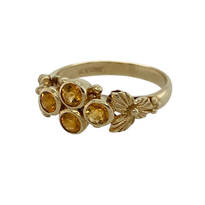 Brighten your jewellery collection with this pre-owned 9ct yellow gold citrine cluster flower ring, featuring a beautiful floral-inspired design with vibrant golden citrine gemstones and delicate decorative shoulders.

Design: The ring showcases a charming flower-style cluster formed from four round citrine gemstones, each measuring approximately 4mm in diameter. Decorative flower detailing on the shoulders enhances the floral theme, creating an elegant and distinctive design.