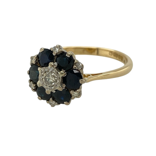 Make a striking statement with this pre-owned 18ct yellow gold diamond and sapphire cluster ring, featuring a luxurious floral-inspired cluster of rich blue sapphires and sparkling diamonds.

Design: The ring showcases an elegant cluster design measuring approximately 13mm high across the front. A sparkling central diamond is surrounded by deep blue sapphires, with additional smaller diamonds set between the sapphires to enhance the brilliance and create a beautifully balanced, eye-catching display.