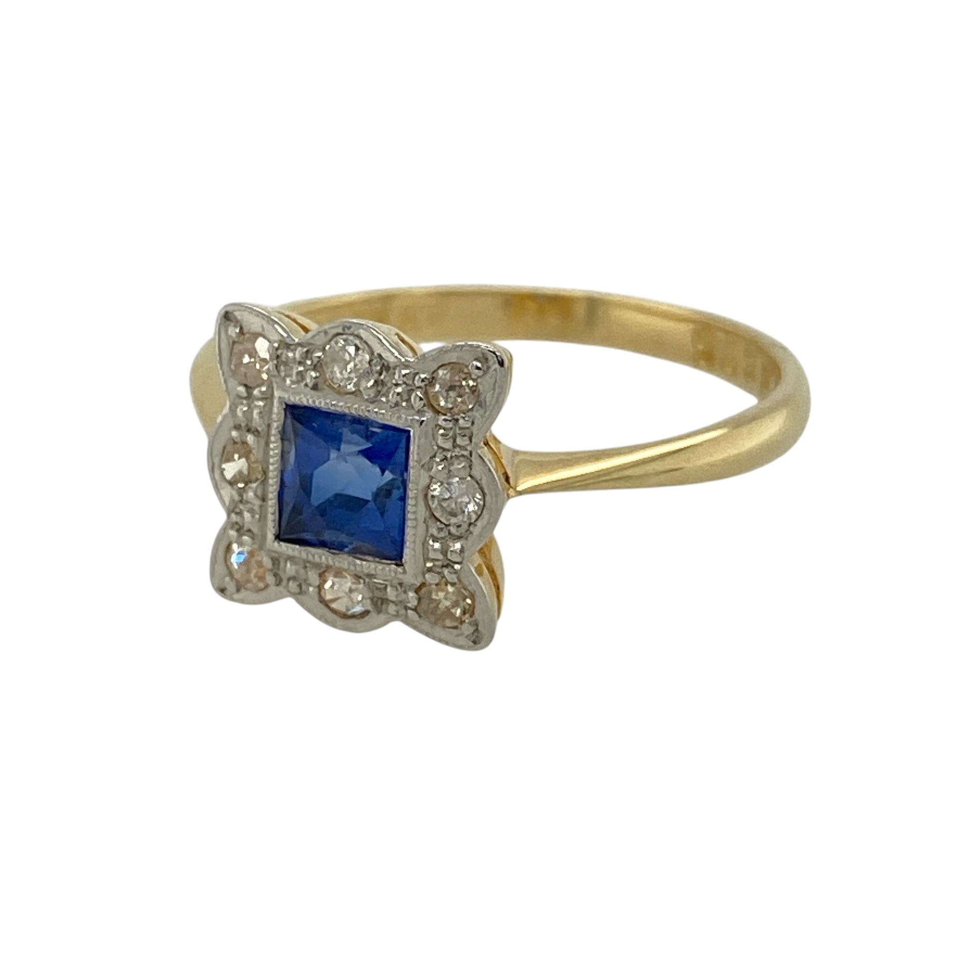 Discover timeless elegance with this pre-owned 18ct yellow gold and platinum diamond and sapphire cluster ring, featuring a striking square-cut sapphire surrounded by sparkling diamonds in a classic vintage-inspired design.

Design: The ring showcases a beautiful square-cut sapphire measuring approximately 4mm by 4mm, surrounded by a sparkling cluster of diamonds that enhance its rich blue colour. Measuring approximately 10mm high across the front