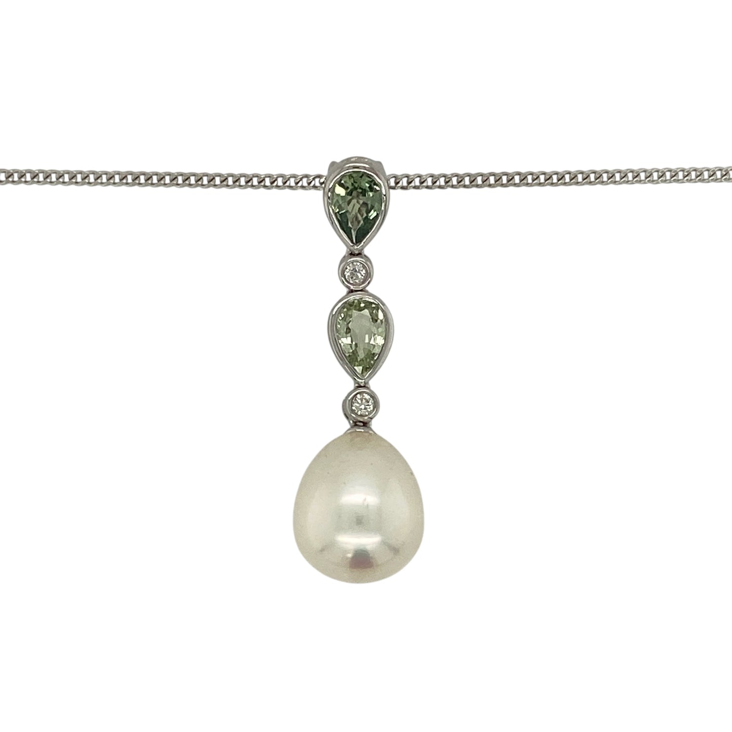 Make a sophisticated statement with this pre-owned 18ct white gold diamond, pearl and green stone pendant necklace, featuring an elegant combination of lustrous pearl, vibrant teardrop gemstones and sparkling diamond accents.

Design: The pendant showcases a beautiful lustrous pearl measuring approximately 13mm by 11mm, suspended beneath two elegant teardrop-shaped green stones, each measuring approximately 6mm by 4mm.