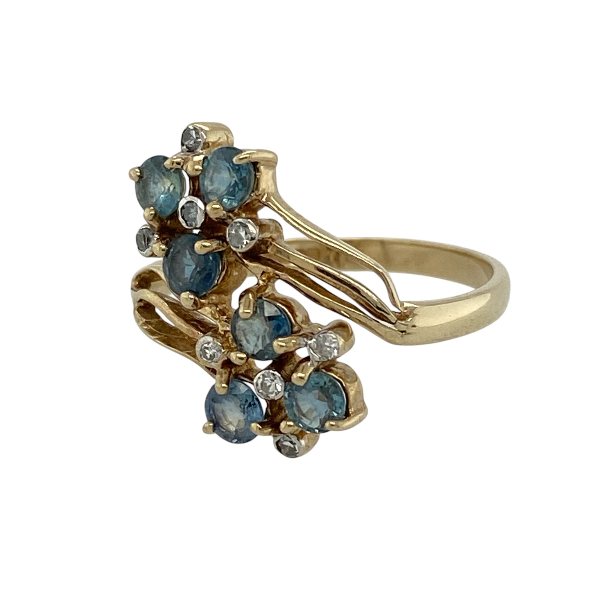 Add vibrant colour and vintage-inspired elegance to your jewellery collection with this pre-owned 9ct yellow gold diamond and sapphire double cluster flower twist ring, featuring a distinctive floral design with an eye-catching profile.

Design: The ring showcases an elegant double flower cluster arrangement set within a graceful twist-style design. The two floral clusters create an attractive statement across the finger, while the flowing twist setting adds movement and distinctive character.