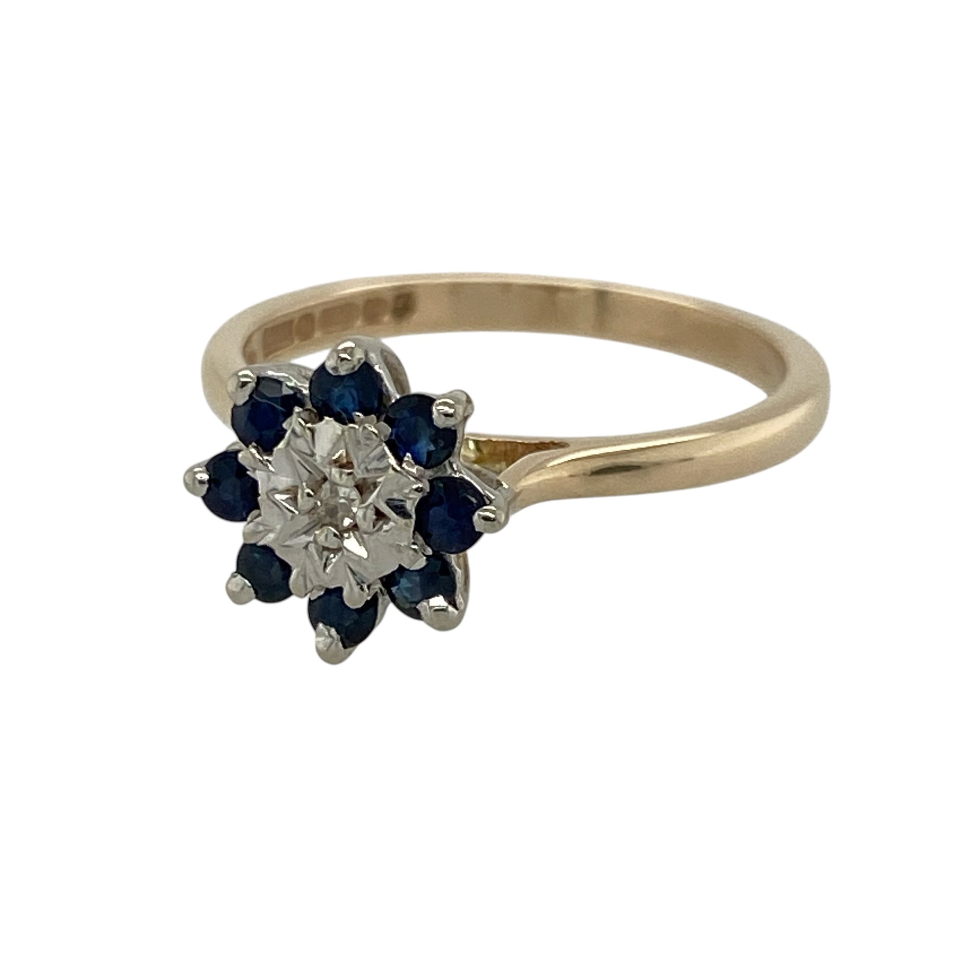 Add classic gemstone colour and refined sparkle to your jewellery collection with this pre-owned 9ct yellow gold diamond and sapphire cluster ring, featuring a traditional design with an illusion-set diamond centre.

Design: The ring showcases a classic cluster design centred around a white gold illusion-set diamond, surrounded by round sapphires that create an attractive contrast of sparkle and rich gemstone colour.