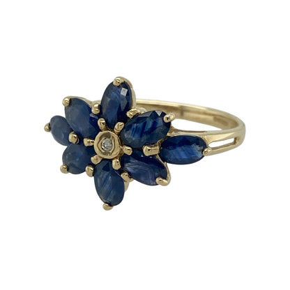 Bring a touch of floral elegance to your jewellery collection with this pre-owned 9ct yellow gold diamond and sapphire flower style ring, featuring a beautiful arrangement of marquise cut sapphires surrounding a sparkling diamond.

Design: The eye-catching flower-inspired design measures approximately 14mm high and is formed from marquise cut sapphires radiating around a central diamond, creating a timeless and elegant statement piece.