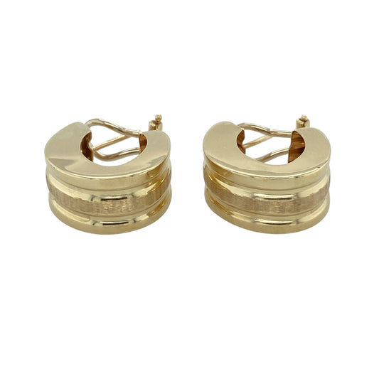 This pair of pre-owned 9ct yellow gold wide textured oval earrings makes a bold statement with its striking shape and beautifully detailed finish.

Design: Featuring a wide oval design with an attractive textured finish, these earrings reflect the light from every angle for added depth and sparkle. Their substantial profile and timeless styling make them perfect for both everyday wear and special occasions.
Material: Made from 9-carat yellow gold with a clip style earring fastening.