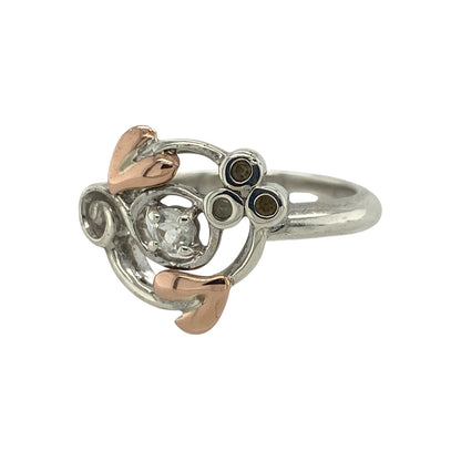 Elegant and symbolic, this pre-owned Clogau Tree of Life ring blends sterling silver, 9ct rose gold, and sparkling white topaz—perfect for meaningful style with a refined finish.

Design: The ring features a 3mm round white topaz stone at the centre, framed by a flowing Tree of Life design in 925 silver with delicate 9ct rose gold detailing.
Material: Made from sterling silver and 9-carat rose gold, the polished finish highlights the soft contrast between metals and the brilliance of the topaz.