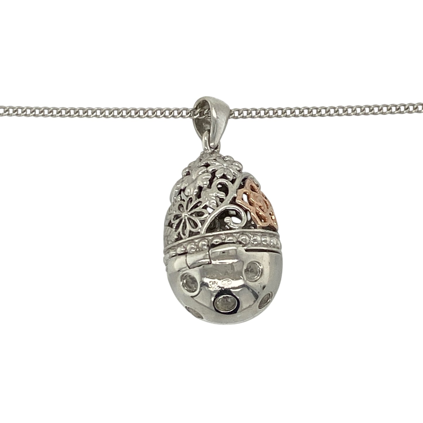 This pre-owned Clogau hinged egg pendant necklace is a distinctive sterling silver and 9ct rose gold design, featuring white topaz, floral detailing and a hidden heart drop inside.

Design: Featuring a patterned egg-shaped pendant decorated with floral detailing and sparkling white topaz, this Clogau design opens on a hinge to reveal a delicate heart drop hidden inside. The pendant measures approximately 2.7cm long including the bail and is suspended from an adjustable Clogau curb chain