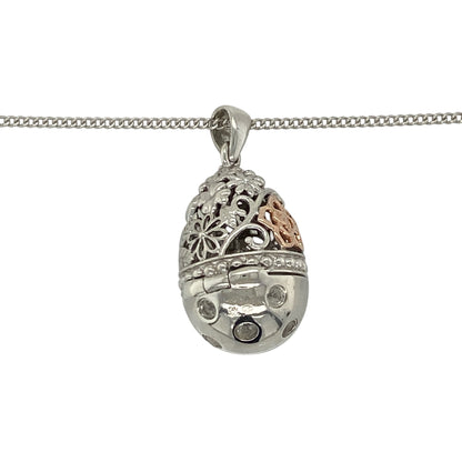 This pre-owned Clogau hinged egg pendant necklace is a distinctive sterling silver and 9ct rose gold design, featuring white topaz, floral detailing and a hidden heart drop inside.

Design: Featuring a patterned egg-shaped pendant decorated with floral detailing and sparkling white topaz, this Clogau design opens on a hinge to reveal a delicate heart drop hidden inside. The pendant measures approximately 2.7cm long including the bail and is suspended from an adjustable Clogau curb chain