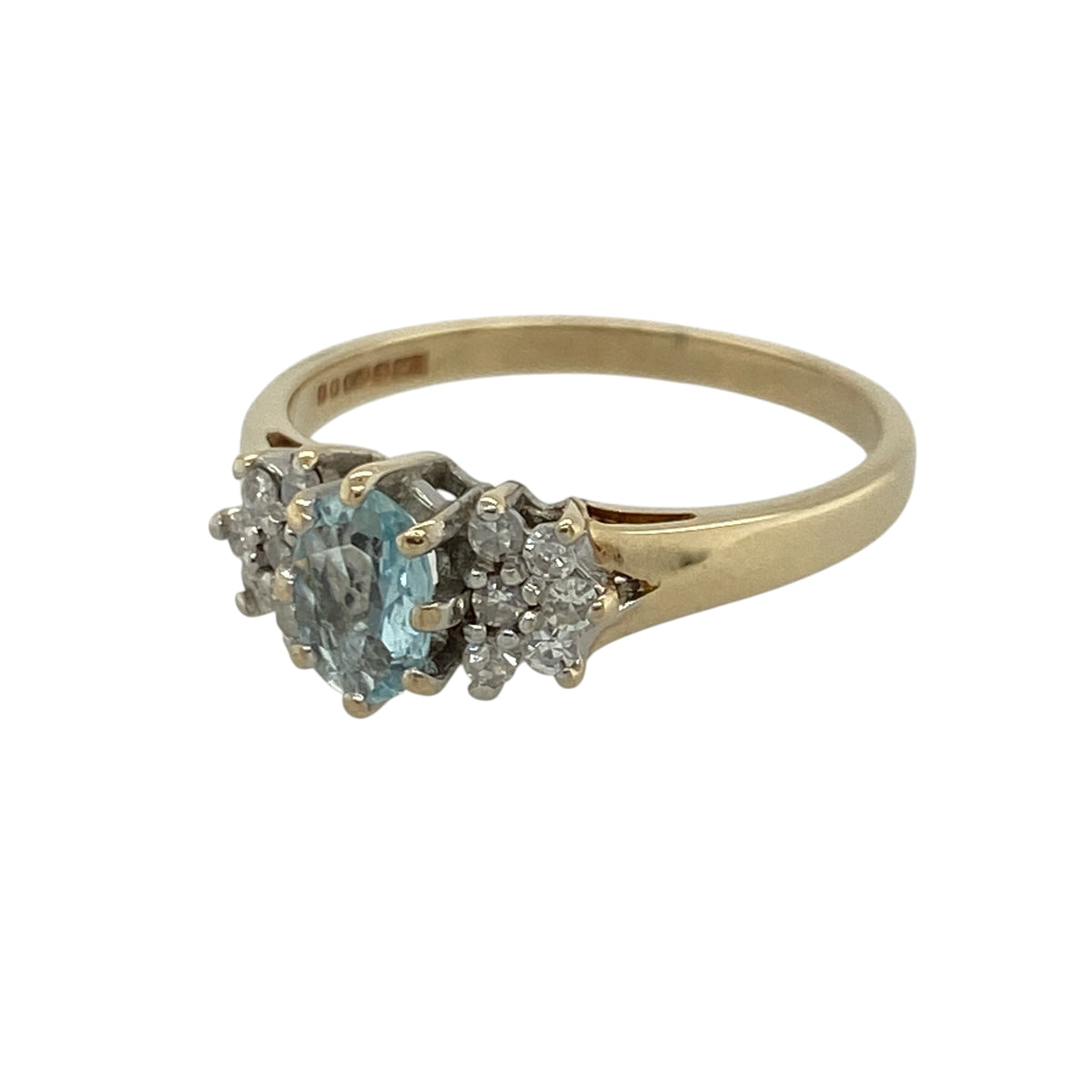 This pre-owned 9ct yellow gold diamond and blue topaz ring is a colourful design, featuring a central oval blue topaz accented by small diamond clusters.

Design: Featuring an oval blue topaz at the centre with a small diamond cluster set on either side, this ring combines the bright blue tones of topaz with classic yellow gold and delicate diamond detail.
Material: Made from 9-carat yellow gold.