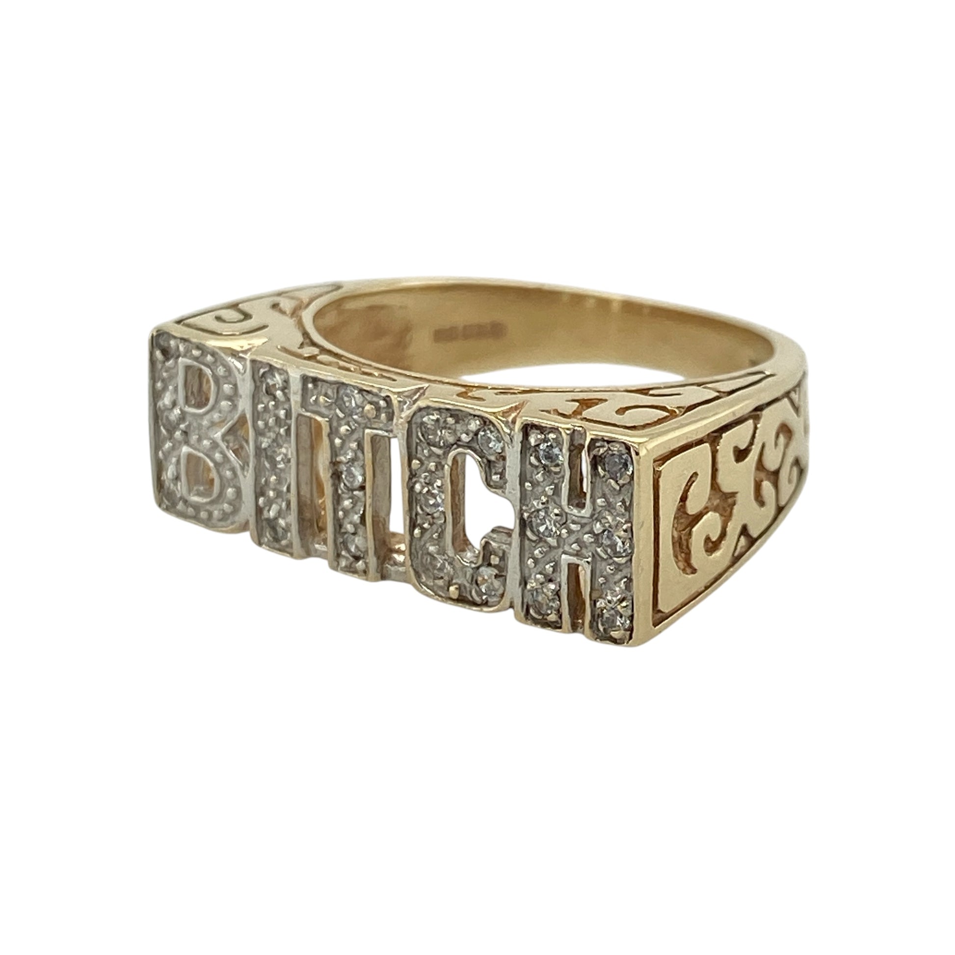 This pre-owned 9ct yellow and white gold cubic zirconia ‘Bitch’ ring is a bold statement design, combining two-tone gold with sparkling stone detailing.

Design: Featuring the word ‘Bitch’ across the front, this distinctive ring combines yellow and white gold with cubic zirconia detailing for an eye-catching finish. The front of the ring measures approximately 8mm high, creating a fun statement piece with plenty of character.
Material: Made from 9-carat yellow and white gold.