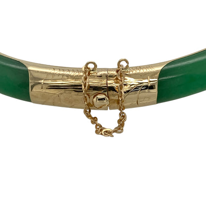 This pre-owned 14ct yellow gold and jade hinged bangle is a distinctive design, combining rich green jade with decorative yellow gold detailing.

Design: Featuring jade sections complemented by patterned yellow gold detailing, this substantial bangle has a hinged design for easier wear. Measuring approximately 7mm wide, it offers a bold look while showcasing the rich green tones of the jade against warm yellow gold.
Material: Made from 14-carat yellow gold with jade.
Gemstone Detail: Set with green jade.