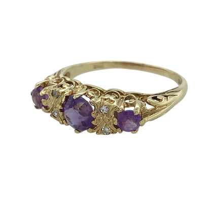 This pre-owned 9ct yellow gold diamond and amethyst vintage style ring is a decorative design, featuring three round amethyst stones with diamond detailing.

Design: Featuring a central round amethyst with two diamonds on either side and a round amethyst at each end, this ring has a vintage-inspired arrangement finished in warm 9ct yellow gold.
Material: Made from 9-carat yellow gold.
Gemstone Detail: Centre round amethyst measures approximately 5mm in diameter, with four diamonds and a round amethyst