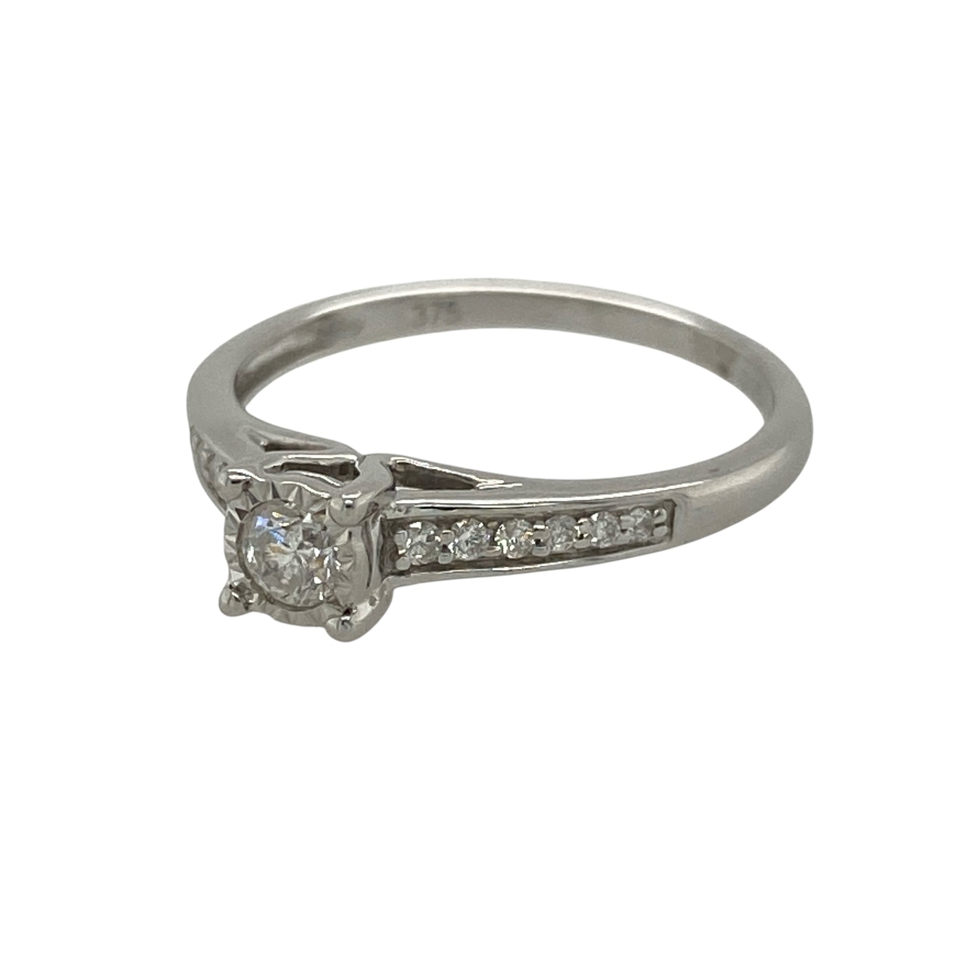 This pre-owned 9ct white gold diamond illusion set solitaire ring is an elegant design, featuring an illusion set centre with additional diamonds along the shoulders.

Design: Featuring an illusion set solitaire-style centre with diamond set shoulders, this ring creates a detailed diamond look finished in 9ct white gold.
Material: Made from 9-carat white gold.
Gemstone Detail: Approximately 0.25ct of diamond content set in total, including the centre and shoulder diamonds.