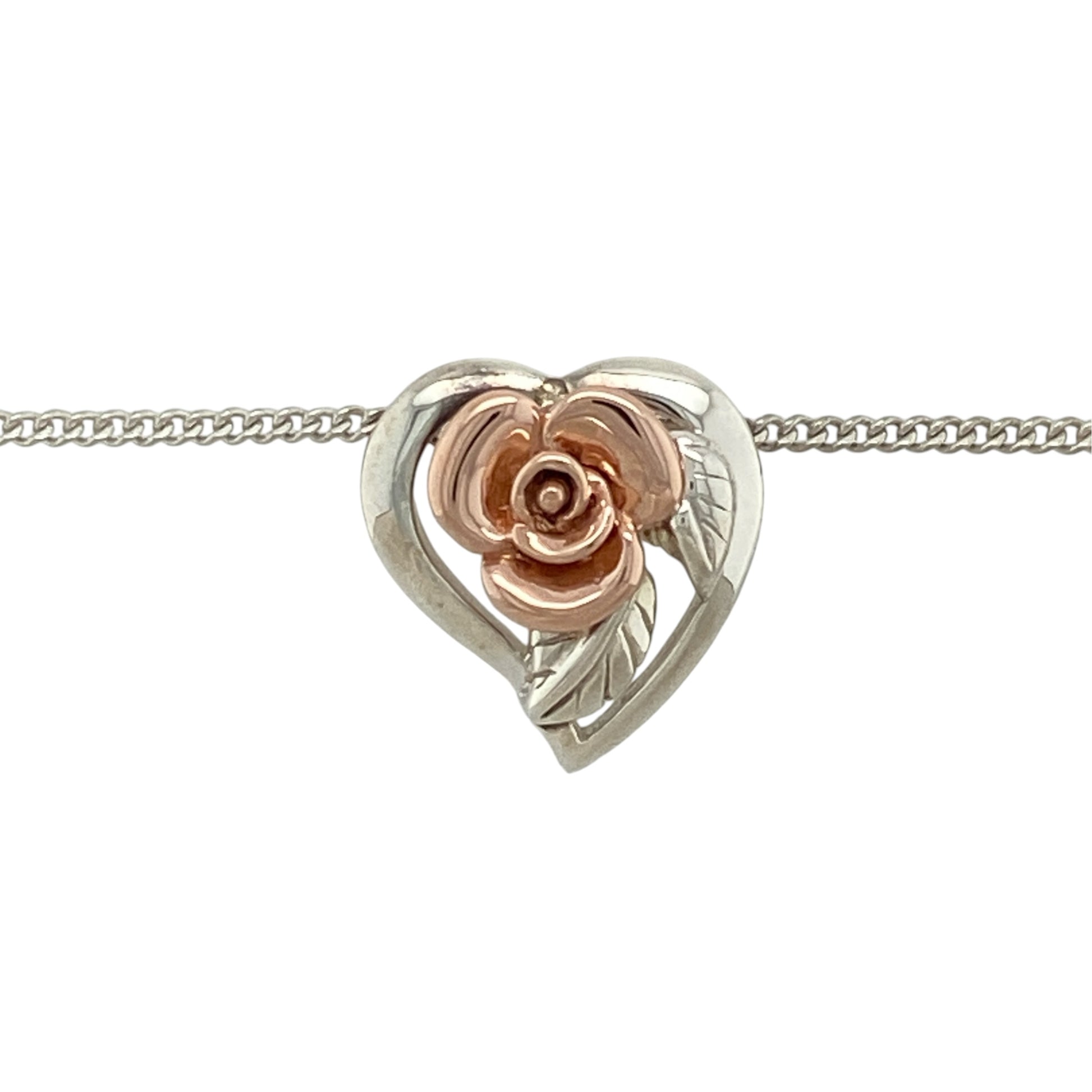 This pre-owned Clogau heart rose flower pendant necklace is a romantic two-tone design, combining 925 silver with signature 9ct rose gold detailing.

Design: Featuring a heart-shaped pendant with a decorative rose flower design, this Clogau necklace combines polished silver with contrasting rose gold detailing on an 18-inch curb chain.
Material: Made from 925 sterling silver with 9-carat rose gold detailing.
Pendant Detail: Heart-shaped rose flower pendant measuring approximately 1.5cm long.