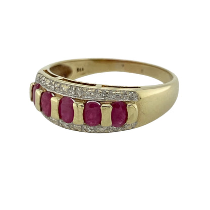 This pre-owned 9ct yellow gold diamond and ruby band ring is a colourful gemstone design, featuring five oval rubies with diamond detailing.

Design: Featuring five oval ruby stones set across the front with small diamonds above and below, this band ring combines rich red tones with the warm finish of 9ct yellow gold.
Material: Made from 9-carat yellow gold.
Gemstone Detail: Five oval ruby stones each measuring approximately 4mm by 3mm, with small diamonds set above and below.