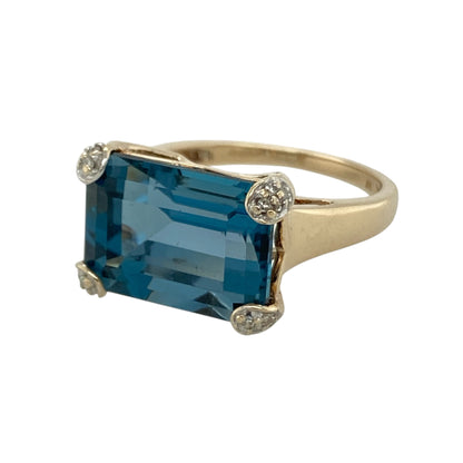 This pre-owned 9ct yellow gold diamond and blue topaz ring is a bold gemstone design, featuring a large rectangular blue topaz with diamond detailing.

Design: Featuring a rectangular blue topaz centre stone with diamond detailing, this ring combines bright blue tones with the warm finish of 9ct yellow gold.
Material: Made from 9-carat yellow gold.
Gemstone Detail: Rectangular blue topaz stone measuring approximately 10mm by 14mm with diamond detailing.
Ring Detail: Blue topaz and diamond ring design.