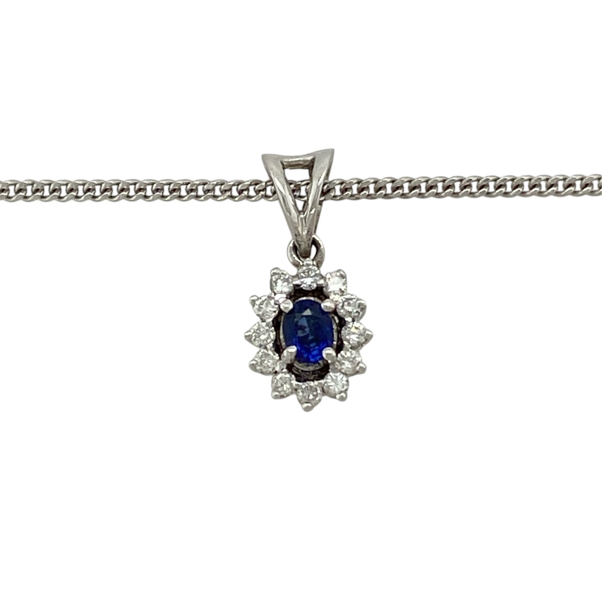 This pre-owned 9ct white gold diamond and sapphire cluster pendant necklace is a classic gemstone design, featuring an oval sapphire with diamond detailing.

Design: Featuring an oval sapphire centre stone surrounded by diamond detailing in a cluster setting, this pendant is finished in 9ct white gold and suspended from an 18-inch curb chain.
Material: Made from 9-carat white gold.
Gemstone Detail: Oval sapphire measuring approximately 4mm by 3mm with diamonds set around.