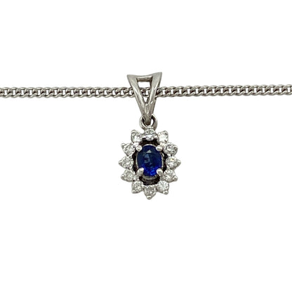 This pre-owned 9ct white gold diamond and sapphire cluster pendant necklace is a classic gemstone design, featuring an oval sapphire with diamond detailing.

Design: Featuring an oval sapphire centre stone surrounded by diamond detailing in a cluster setting, this pendant is finished in 9ct white gold and suspended from an 18-inch curb chain.
Material: Made from 9-carat white gold.
Gemstone Detail: Oval sapphire measuring approximately 4mm by 3mm with diamonds set around.