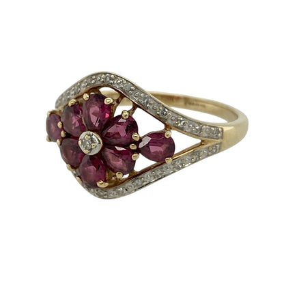 This pre-owned 9ct yellow gold diamond and ruby flower ring is a colourful floral design, featuring ruby and diamond detailing.

Design: Featuring a decorative flower-shaped design set with rubies and diamonds, this ring combines rich red tones with the warm finish of 9ct yellow gold.
Material: Made from 9-carat yellow gold.
Gemstone Detail: Set with ruby and diamond stones in a flower-style arrangement.
Ring Detail: Front of the ring measures approximately 14mm high.