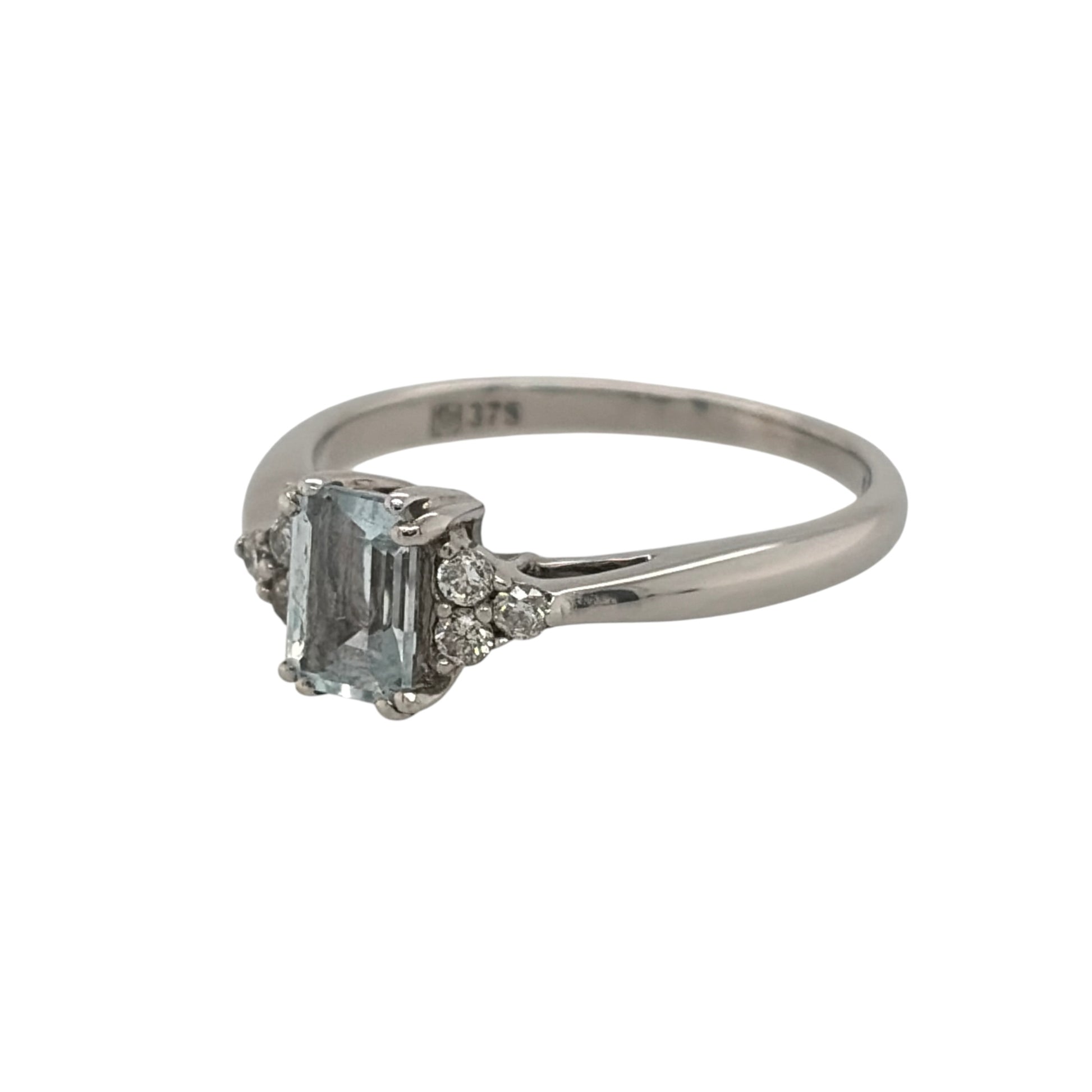 This pre-owned 9ct white gold diamond and aquamarine-coloured stone ring is a classic gemstone design, featuring a rectangular centre stone complemented by diamond detailing.

Design: Featuring a rectangular aquamarine-coloured centre stone, this ring has three diamonds set on either side for a balanced design in 9ct white gold.
Material: Made from 9-carat white gold.
Gemstone Detail: Set with a rectangular aquamarine-coloured stone measuring approximately 6mm by 4mm, with three diamonds set on either side.