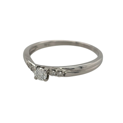 This pre-owned 9ct white gold diamond solitaire twist ring is a classic design, featuring a brilliant cut centre diamond complemented by smaller diamond detailing.

Design: Featuring a twist-style solitaire design, this ring showcases a brilliant cut centre diamond with two smaller diamonds set on each side.
Material: Made from 9-carat white gold.
Gemstone Detail: Set with a central brilliant cut diamond of approximately 0.20ct, complemented by four smaller diamonds, with two set on each side.