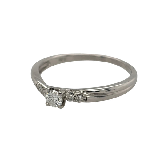 This pre-owned 9ct white gold diamond solitaire twist ring is a classic design, featuring a brilliant cut centre diamond complemented by smaller diamond detailing.

Design: Featuring a twist-style solitaire design, this ring showcases a brilliant cut centre diamond with two smaller diamonds set on each side.
Material: Made from 9-carat white gold.
Gemstone Detail: Set with a central brilliant cut diamond of approximately 0.20ct, complemented by four smaller diamonds, with two set on each side.