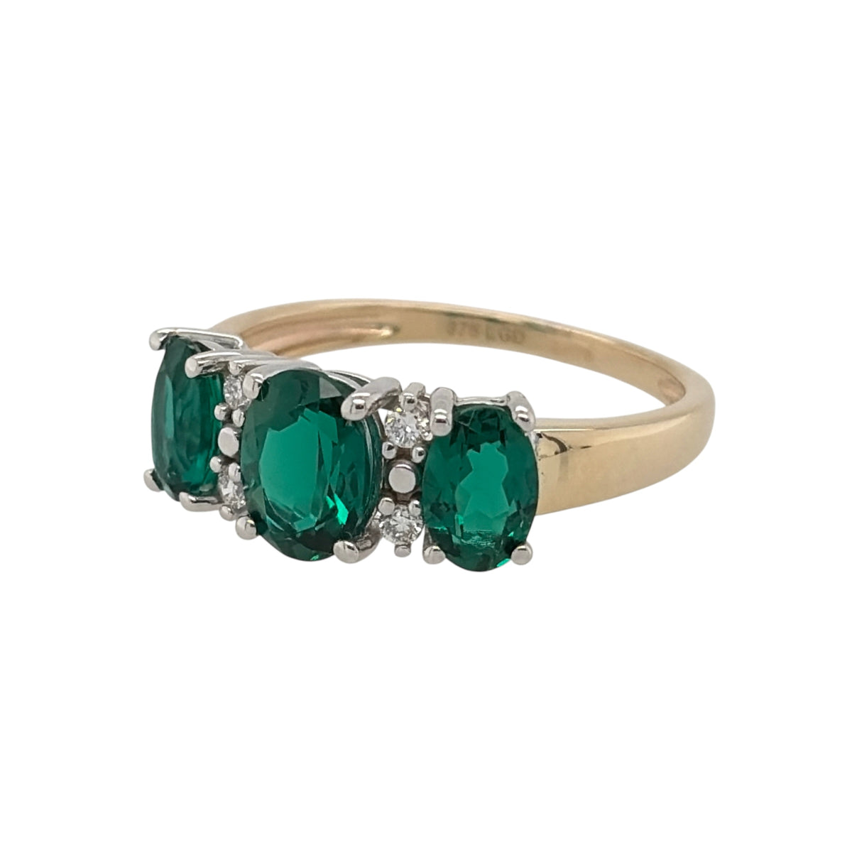 New 9ct Gold Lab Grown Diamond &amp; Lab Grown Emerald Trilogy Cluster Ring in various sizes with the approx weight 2.25 grams. There is approximatley 0.20ct of lab grown diamond content in the ring has approximate clarity i2 and colour J. The center lab grown emerald oval stone is 7mm by 5mm and the side ones are 6mm by 4mm