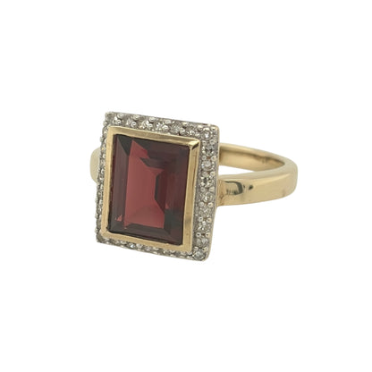 This pre-owned 9ct yellow gold diamond and garnet cluster ring is a striking gemstone design, featuring a large rectangular garnet surrounded by diamond detailing.

Design: Featuring a classic cluster design, this ring showcases a rectangular garnet as the centrepiece, surrounded by diamonds and finished in warm 9ct yellow gold.
Material: Made from 9-carat yellow gold.
Gemstone Detail: Set with a rectangular garnet measuring approximately 10mm by 8mm, surrounded by diamond detailing.