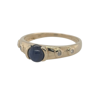 This pre-owned 9ct yellow gold diamond and sapphire band ring is a distinctive gemstone design, featuring a round cabochon sapphire complemented by diamond detailing.

Design: Featuring a classic band-style design, this ring showcases a round cabochon sapphire with diamond detailing in warm 9ct yellow gold.
Material: Made from 9-carat yellow gold.
Gemstone Detail: Set with a round cabochon sapphire measuring approximately 6mm in diameter, complemented by diamond detailing.