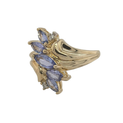 This pre-owned 9ct yellow gold diamond and tanzanite dress ring is a striking statement design, featuring five marquise cut tanzanite stones complemented by diamond detailing.

Design: Featuring a bold dress ring design, this ring has five marquise cut tanzanite stones arranged across the front with diamond detailing in warm 9ct yellow gold.
Material: Made from 9-carat yellow gold.
Gemstone Detail: Set with five marquise cut tanzanite stones, complemented by diamond detailing.