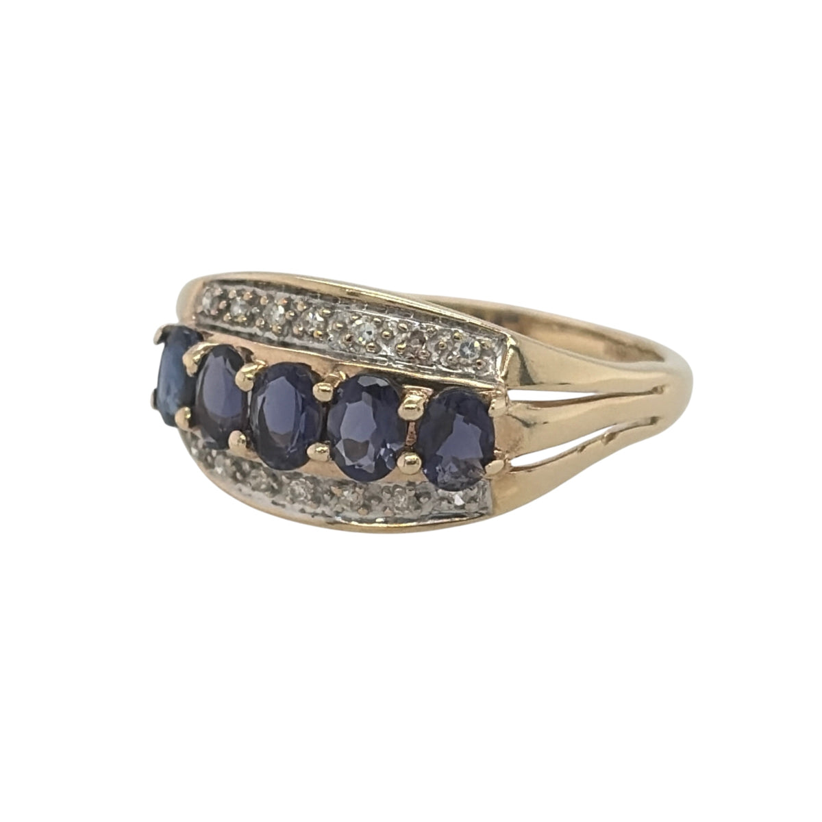 This pre-owned 9ct yellow gold diamond and iolite band ring is a distinctive gemstone design, featuring oval iolite stones complemented by diamond detailing.

Design: Featuring a wide gemstone band design, this ring has oval iolite stones arranged across the front with diamond detailing in warm 9ct yellow gold.
Material: Made from 9-carat yellow gold.
Gemstone Detail: Set with oval iolite stones measuring approximately 4mm by 3mm each, complemented by diamond detailing.