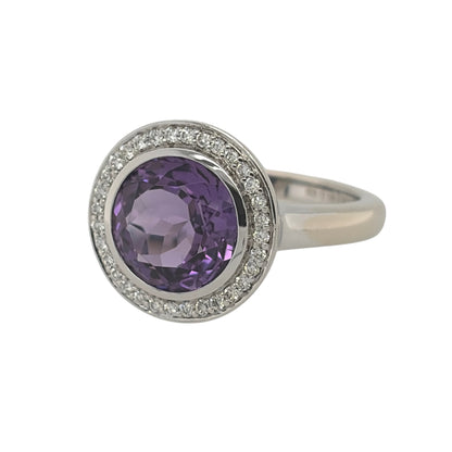 This pre-owned 18ct white gold diamond and amethyst halo ring is a striking statement design, featuring a large round amethyst surrounded by diamond detailing.

Design: Featuring a classic halo design, this ring showcases a large round amethyst as the centrepiece, surrounded by diamonds and finished in 18ct white gold.
Material: Made from 18-carat white gold.
Gemstone Detail: Set with a round amethyst measuring approximately 10mm in diameter, surrounded by diamond detailing.