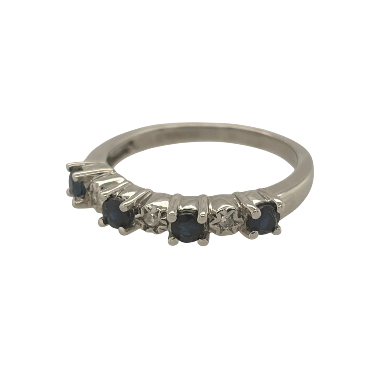 This pre-owned 9ct white gold diamond and sapphire band ring is a classic gemstone design, featuring four round sapphires complemented by diamond detailing.

Design: Featuring a traditional gemstone band design, this ring has four round sapphires arranged across the front with diamond detailing in 9ct white gold.
Material: Made from 9-carat white gold.
Gemstone Detail: Set with four round sapphires measuring approximately 3mm in diameter each, complemented by diamond detailing.