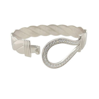 This new 925 sterling silver cubic zirconia set horseshoe twisted bangle is a substantial statement design, featuring a large horseshoe centrepiece with stone detailing.

Design: Featuring a twisted bangle design with a bold horseshoe centrepiece, this bangle has a polished silver finish with cubic zirconia detailing.
Material: Made from 925 sterling silver.
Gemstone Detail: Set with cubic zirconia stones across the horseshoe design.