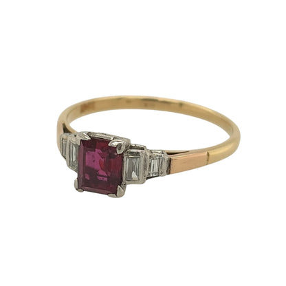 This pre-owned 18ct yellow gold diamond and ruby vintage-style ring is a distinctive gemstone design, featuring an emerald cut ruby with baguette cut diamond detailing.

Design: Featuring a vintage-style setting, this ring showcases a central emerald cut ruby with two baguette cut diamonds set on either side in warm 18ct yellow gold.
Material: Made from 18-carat yellow gold.