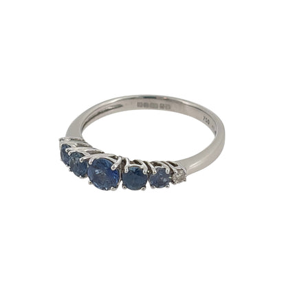 This pre-owned 18ct white gold diamond and blue stone band ring is a distinctive graduated design, featuring blue stones that become lighter and smaller towards each side.

Design: Featuring a graduated gemstone design, this ring has a dark blue centre stone with progressively lighter and smaller blue stones extending outwards, finished with a diamond at each end.
Material: Made from 18-carat white gold.