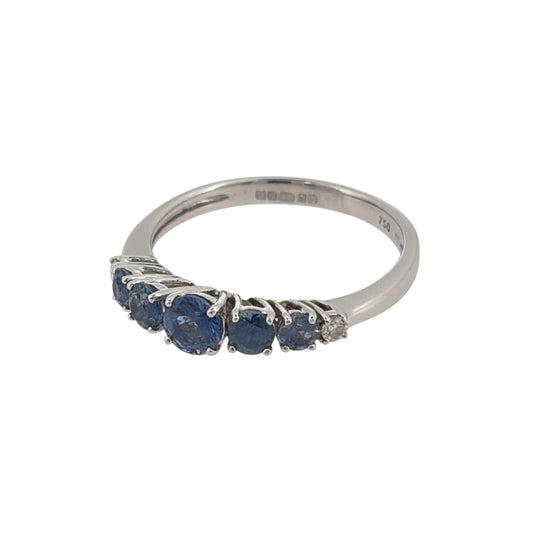 This pre-owned 18ct white gold diamond and blue stone band ring is a distinctive graduated design, featuring blue stones that become lighter and smaller towards each side.

Design: Featuring a graduated gemstone design, this ring has a dark blue centre stone with progressively lighter and smaller blue stones extending outwards, finished with a diamond at each end.
Material: Made from 18-carat white gold.