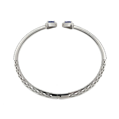 This pre-owned 18ct white gold diamond and tanzanite bangle is a striking torque-style design, featuring tanzanite stones with detailed diamond setting.
Design: Featuring an open torque-style design, this bangle has a triangular tanzanite stone at each end, surrounded by diamonds, with a double row of diamonds extending around half of the bangle.
Material: Made from 18-carat white gold.